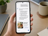 Elinde bir akıllı telefon tutan bir el, ekranda bir yapay zeka yanıtı gösterirken, altında sponsorlu bir reklam yer alıyor