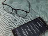 Desenli bir yüzey üzerinde, bir çift gözlüğün yanında ChatGPT uygulaması açık olan bir akıllı telefon