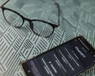 Desenli bir yüzey üzerinde, bir çift gözlüğün yanında ChatGPT uygulaması açık olan bir akıllı telefon