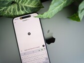 ChatGPT uygulaması açık olan bir akıllı telefon, bitki yapraklarının yanındaki bir dizüstü bilgisayarın üzerinde duruyor