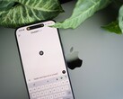 ChatGPT uygulaması açık olan bir akıllı telefon, bitki yapraklarının yanındaki bir dizüstü bilgisayarın üzerinde duruyor