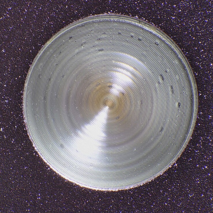 Fresnel lens elemanlarına sahip ve parlama noktalarını önlemek için dokulu bir desene sahip Pixel 9 Pro el feneri açıklığı