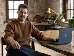 Henry Cavill, elinin altında bir Googlebook ile masada oturuyor.