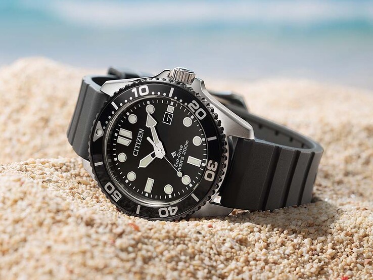 Siyah kadranlı, siyah çerçeveli ve siyah kayışlı Citizen Promaster Marine BN0266-07E, kumun üzerinde duruyor.