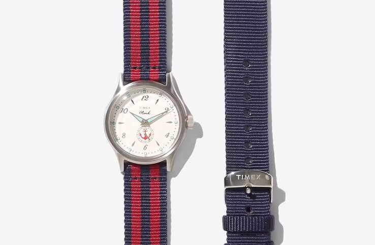 Kırmızı/siyah kumaş kayışlı Noah x Timex MK1 Anchor, düz mavi kayışla birlikte gösterilmiştir.