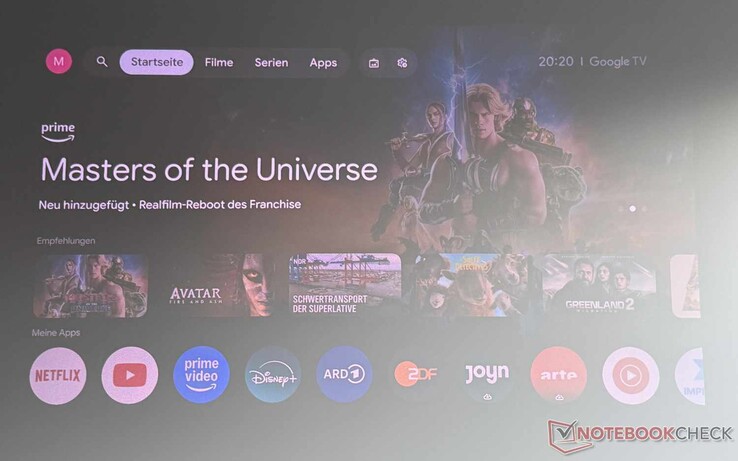 Etoe Dolphin 2'nin Google TV arayüzü (sağ tarafında bir pencere bulunan, ışıklandırması biraz loş bir oda; yüksek kontrastlı ekran)
