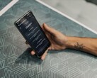 Desenli bir masanın üzerinde ChatGPT uygulaması açık olan bir akıllı telefonu tutan el