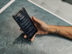 Desenli bir masanın üzerinde ChatGPT uygulaması açık olan bir akıllı telefonu tutan el