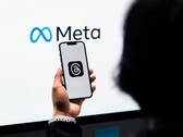 Bir el, büyük bir Meta logosunun önünde bir akıllı telefon tutuyor