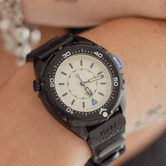 Timex Intrepid x Dimepiece Blackout Edition, siyah paslanmaz çelik kasa, krem rengi kadran ve mor detaylara sahiptir