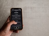 Gri taş bir yüzeyin üzerinde ChatGPT arayüzünü gösteren bir akıllı telefonu tutan el