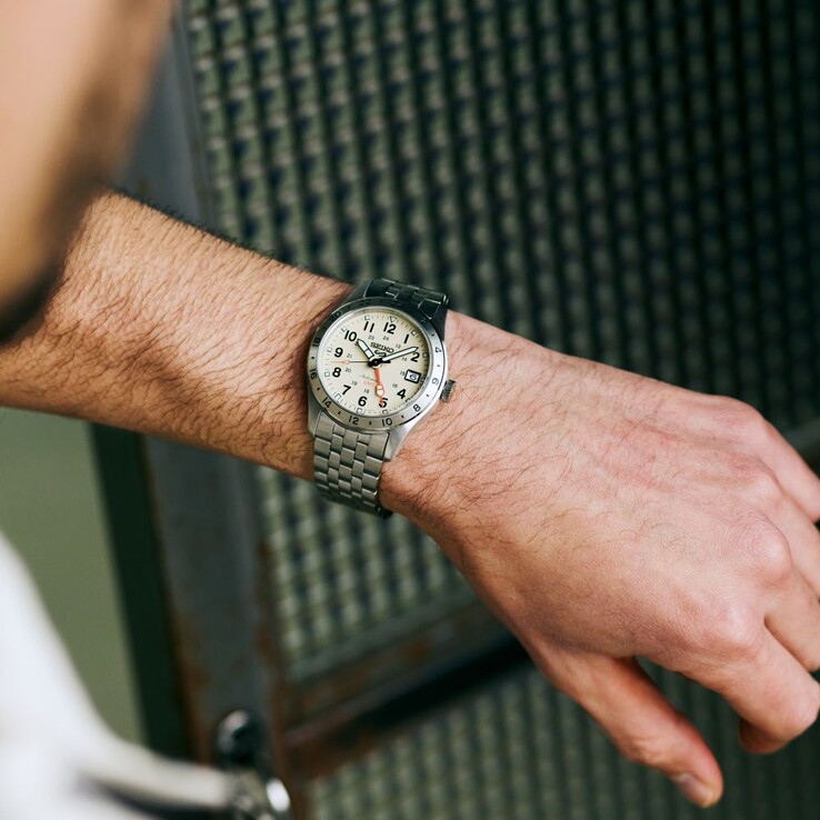 Krem rengi kadranı, turuncu GMT ibresi, sabit 24 saatlik çerçeve ve paslanmaz çelik bileziği ile Seiko 5 Sports Field GMT HDB002 modelinin önden görünümü.