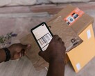 Bir el, bir paketin üzerinde tuttuğu akıllı telefonla barkodunu tarıyor.