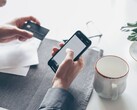 Bir elinde banka kartını tutarken diğer eliyle akıllı telefona dokunan kişi