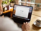 Google ana sayfası açık bir dizüstü bilgisayarın başında oturan, yanında bir fincan kahve bulunan kişi