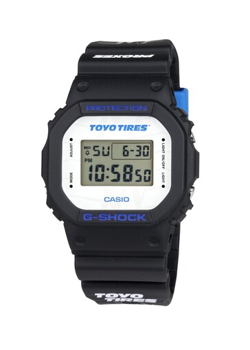 Beyaz kadranda Toyo Tires markası belirgin bir şekilde yer alırken, mavi yazılar klasik kare G-Shock tasarımına kontrast katar.