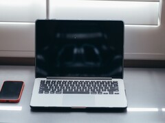 Gün ışığında bir masanın üzerinde dizüstü bilgisayarı ve akıllı telefonu yan yana açın