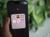 Ekranında yapay zekâ uygulamalarıyla dolu bir klasör bulunan bir akıllı telefonu tutan el