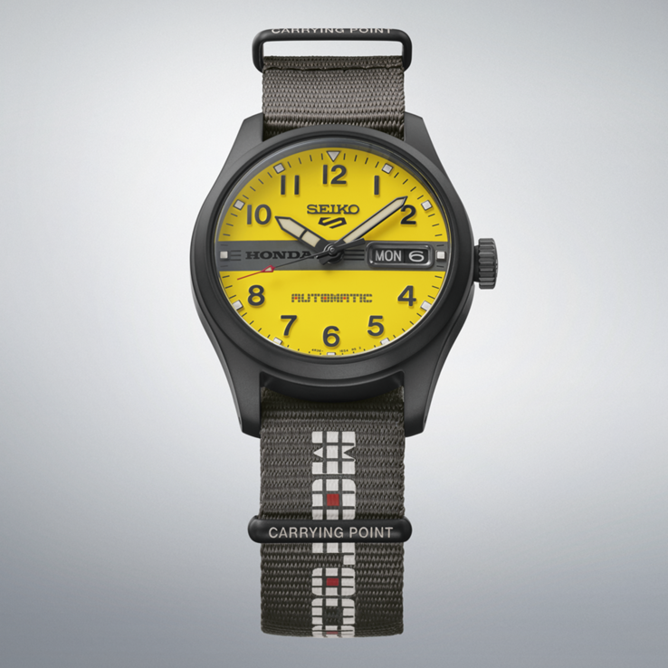 Sarı kadranlı, ortasında siyah Honda logosu bulunan ve gri naylon kayışlı Seiko 5 Sports Field x Honda Motocompo Sınırlı Sürüm modelinin önden görünümü.