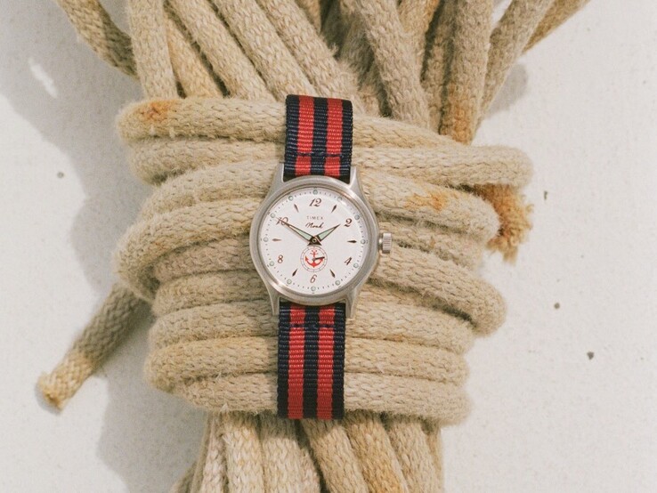 Noah x Timex MK1 Anchor saat: gümüş rengi 36 mm kasa, beyaz kadran, çapa grafiği ve lacivert-kırmızı çizgili kumaş kayış.