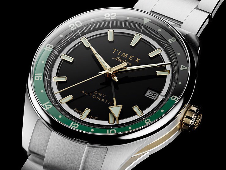 Timex Atelier GMT Première M1a'nın siyah kadranını, yeşil GMT halkasını, altın tonlu kurma kolunu ve paslanmaz çelik bileziğini gösteren açılı görünüm.