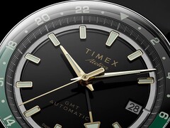 Timex Atelier GMT Première M1a’nın altın tonlu akrep ve yelkovanını, ışıldayan saat imlerini, tarih penceresini ve siyah-yeşil 24 saatlik GMT halkasını gösteren siyah kadranının yakın plan görüntüsü.