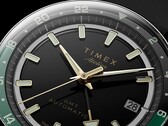 Timex Atelier GMT Première M1a’nın altın tonlu akrep ve yelkovanını, ışıldayan saat imlerini, tarih penceresini ve siyah-yeşil 24 saatlik GMT halkasını gösteren siyah kadranının yakın plan görüntüsü.