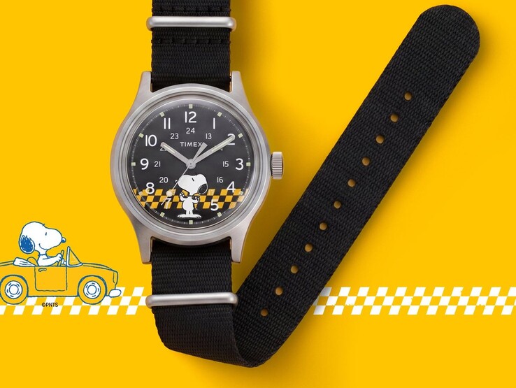 Snoopy figürü ve sarı-siyah kareli desenin yer aldığı siyah kadranlı Peanuts x Timex MK1 saat, sarı arka plan üzerinde siyah kumaş kayışıyla birlikte gösterilmiştir.