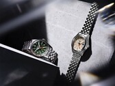 Yeşil kadranlı Seiko 5 Sports Field GMT HDB001 ve krem rengi kadranlı HDB002 modelleri, paslanmaz çelikten beş halkalı bileziklerle yan yana sergileniyor; her ikisi de sabit 24 saatlik çerçeveye ve turuncu GMT ibresine sahip.