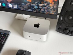 Monitör, klavye, fare ve hoparlör ile donatılmış bir oyun kurulumunda, masanın üzerinde duran Apple M6 Mac mini.