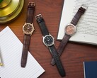 Bir defter, kalem, lamba ve açık bir kitabın yanında ahşap bir masanın üzerinde dizilmiş üç adet Citizen Rolan saat; bunların arasında somon rengi kadranlı AW2110-14Z modeli de bulunuyor.