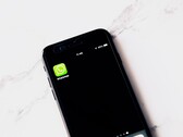 Beyaz bir masanın üzerinde WhatsApp uygulamasını gösteren bir akıllı telefon