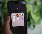 Bir el, Gemini, ChatGPT ve Claude gibi uygulamaların bulunduğu AI adlı bir klasörü gösteren bir akıllı telefonu tutuyor.