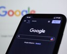 Google logosunun bulunduğu bir ekranın önünde Google arama sayfasını gösteren akıllı telefon