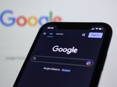 Google logosunun bulunduğu bir ekranın önünde Google arama sayfasını gösteren akıllı telefon