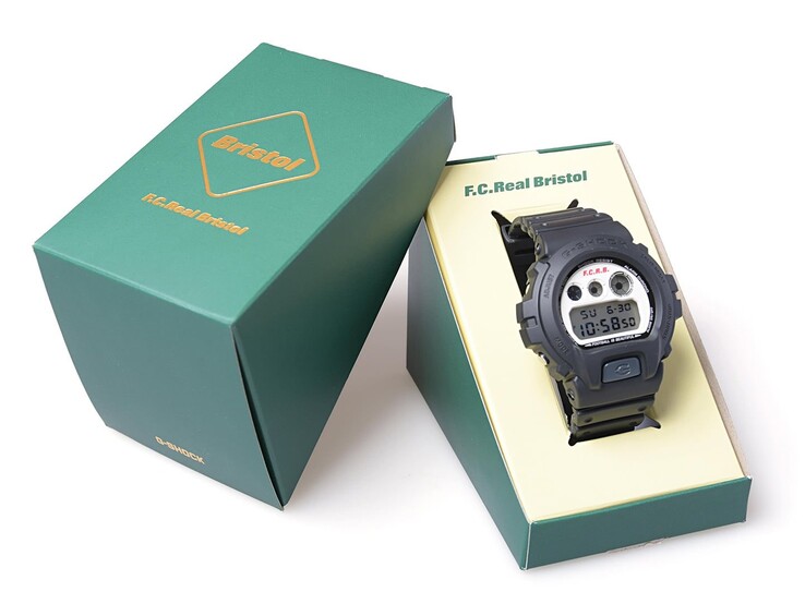 Casio G-Shock x F.C. Real Bristol DW-6900, yeşil renkli ortak markalı bir sunum kutusunun içinde sergileniyor; yanında ise buna uygun bir dış kılıf bulunuyor.