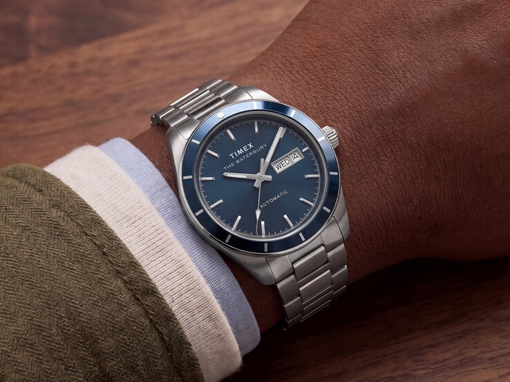 Mavi emaye kadranlı Timex Waterbury Heritage Automatic saat, bileğinde takılıyken gümüş rengi kasası ve paslanmaz çelik bileziği ile görülüyor.