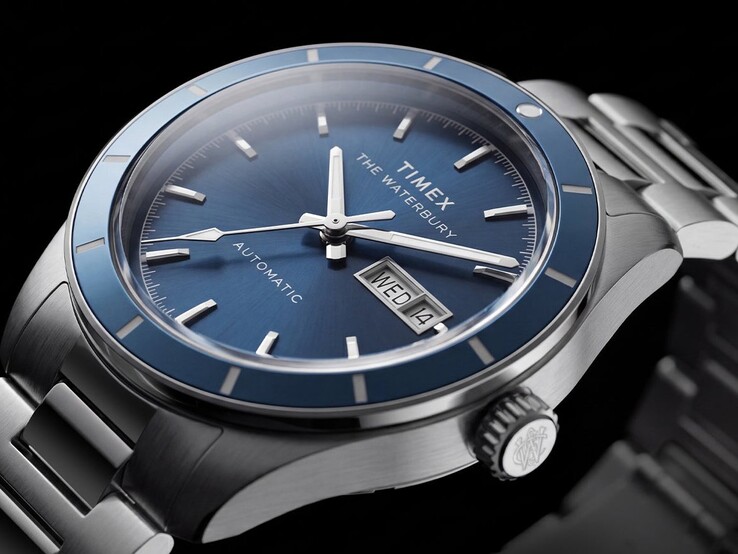 Mavi kadranlı Timex Waterbury Heritage Automatic saatinin, ışıklı ibrelerini, uygulanan saat işaretlerini ve gün-tarih göstergesini gösteren yakın çekim görüntüsü.