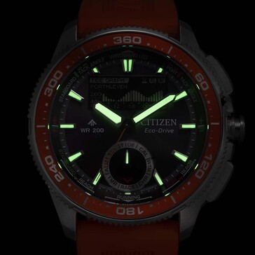Citizen Promaster Wave Tracker JV3000-13E'nin karanlık bir arka plana karşı parlayan ibreleri ve saat imlerini gösteren düşük ışıklı lümen çekimi.