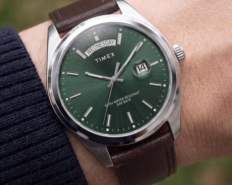 Yeşil güneş ışını desenli kadranıyla bir bilekte Timex Legacy Day and Date.