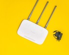 Sarı arka plan üzerinde üç anteni ve bir güç kaynağı bulunan beyaz Wi-Fi yönlendirici