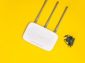 Sarı arka plan üzerinde üç anteni ve bir güç kaynağı bulunan beyaz Wi-Fi yönlendirici