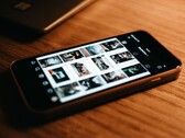 Ahşap bir masanın üzerinde duran bir akıllı telefon; ekranında bir dizi fotoğraf görünüyor