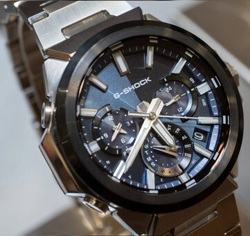 Mavi kadranlı Casio G-Shock GST-W1000AD-2A modelinin yakın çekim görüntüsü; katmanlı üç alt kadran düzeni, ışıklı işaretler, gümüş renkli ibreler ve siyah çerçeve görülmektedir.