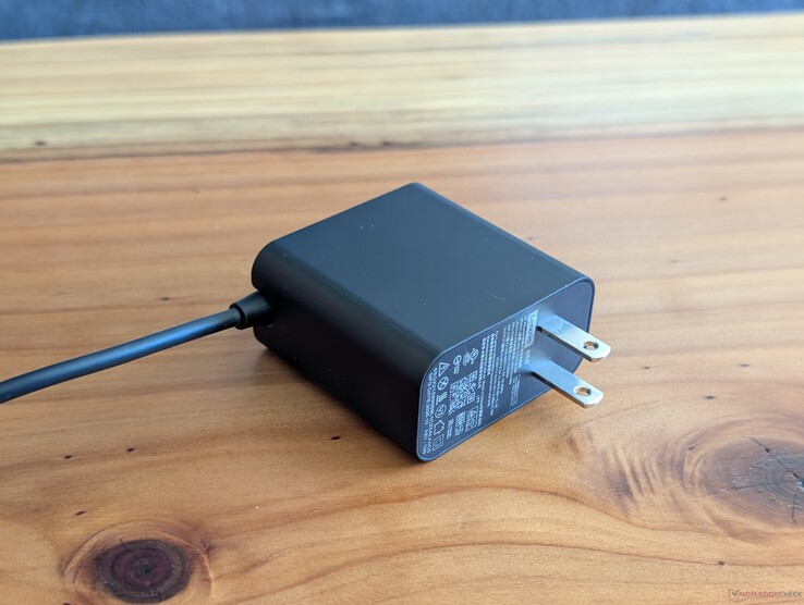 Lenovo Yoga Slim 7 14 ile birlikte gelen 65 W USB-C şarj adaptörü. Geri çekilemeyen şebeke fişlerine ve diğer ucundaki entegre USB-C kablosuna dikkat edin
