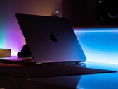 Karanlık bir odada yarı açık bir MacBook; aralıktan masaya ışık sızıyor