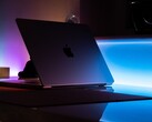 Karanlık bir odada yarı açık bir MacBook; aralıktan masaya ışık sızıyor