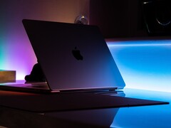 Karanlık bir odada yarı açık bir MacBook; aralıktan masaya ışık sızıyor