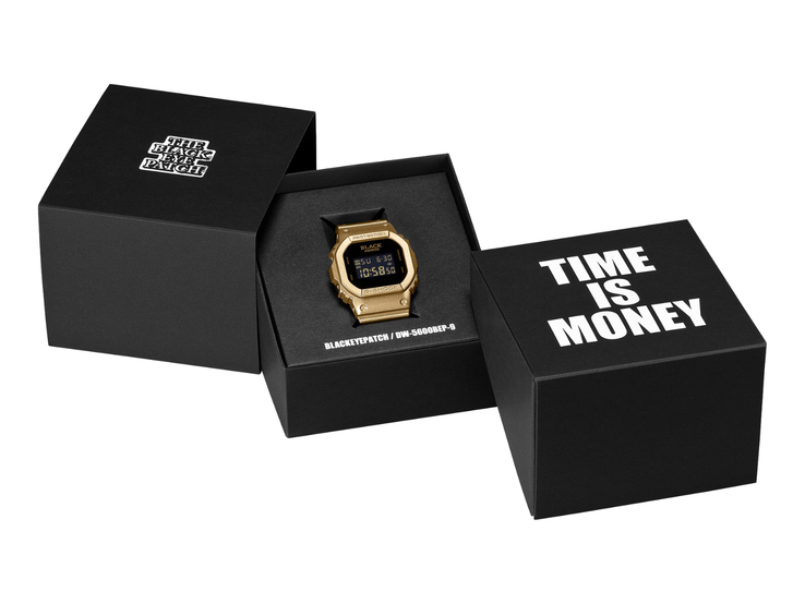 Siyah dijital ekrana sahip altın renkli bir Casio G-Shock DW-5600BEP-9 saat, iki siyah sunum kutusunun arasında yer almaktadır. Saatin kadranında BlackEyePatch markası bulunurken, ön plandaki kutuda “TIME IS MONEY” yazmaktadır.