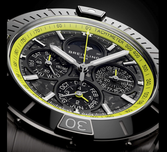 Breitling Super Chronomat B19 44 Perpetual Calendar Chronograph’ın karbon fiber kadranını, takvim alt kadranlarını, gümüş tonlu ibrelerini ve limon yeşili takimetre ölçeğini gösteren yakın çekimi.